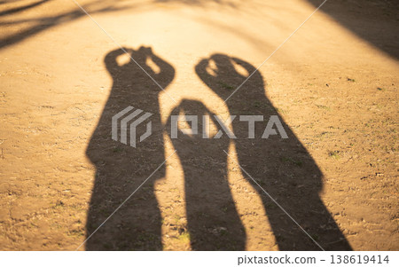 The shadows of family members' hands are cast on the ground. 138619414