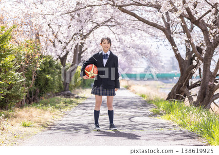 一名身穿校服的中學生女生在櫻桃樹下抱著籃球。 一名身穿校服的中學生女生在櫻桃樹下抱著籃球。 138619925