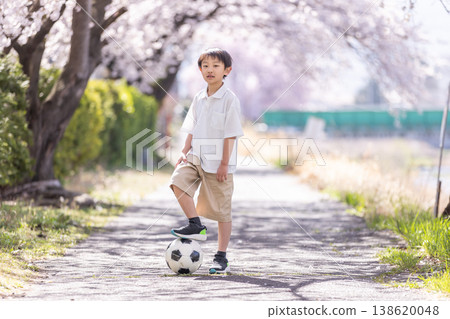 A boy kicking a soccer ball under a cherry tree. A boy kicking a soccer ball under a cherry tree. 138620048