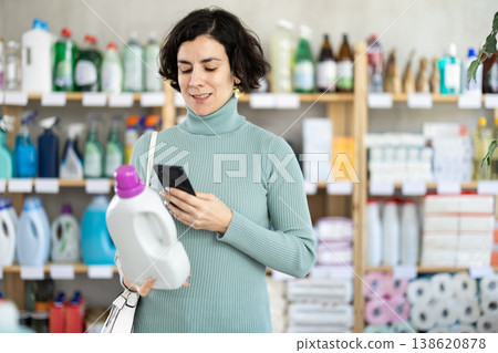 Middle-aged woman scanning QR-code on detergent at supermarket Middle-aged woman scanning QR-code on detergent at supermarket 138620878