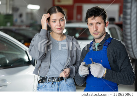 Man car mechanic talks with girl client in workshop and takes order. Man car mechanic talks with girl client in workshop and takes order. 138620965