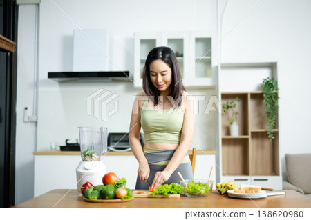 Fit woman preparing fresh salad with vegetables on wooden cutting board in kitchen. Concept of healthy food, clean eating, and fitness lifestyle. 138620980