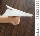 A child's hand holding a paper airplane 138621149