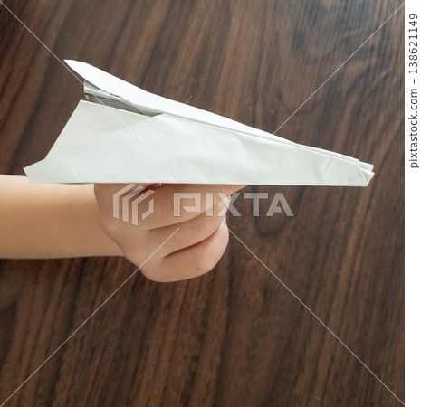 A child's hand holding a paper airplane A child's hand holding a paper airplane 138621149