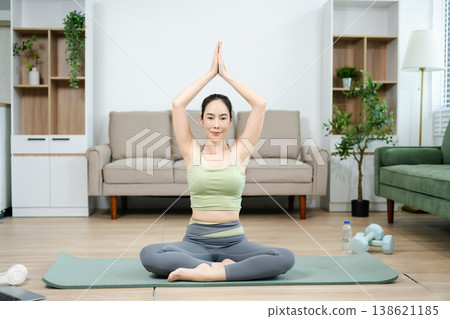 Asian woman practicing yoga at home. Healthy aging, wellness, balance, and mindfulness lifestyle in a calm living space. Asian woman practicing yoga at home. Healthy aging, wellness, balance, and mindfulness lifestyle in a calm living space. 138621185