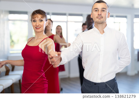 Woman in red enjoying slow foxtrot with partner in dance studio Woman in red enjoying slow foxtrot with partner in dance studio 138621279
