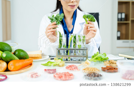 Nutritionist in safety goggles analyzing kale and vegetables in a food science lab. Health, diet, research, and clean eating concept. Clinical setting 138621299