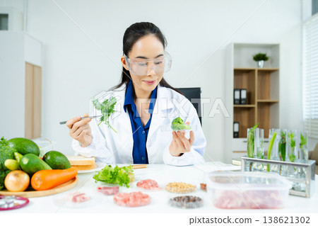 Nutritionist in safety goggles analyzing kale and vegetables in a food science lab. Health, diet, research, and clean eating concept. Clinical setting 138621302