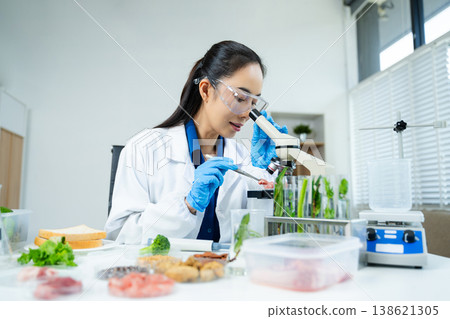Female scientist analyzing vegetables and food samples in laboratory, researching nutrition, biotechnology, and food safety innovation. 138621305