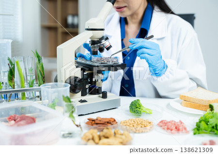 Closeup female scientist testing raw meat in biotechnology lab for food safety, nutrition, and quality research, focusing on food science innovation. Closeup female scientist testing raw meat in biotechnology lab for food safety, nutrition, and quality research, focusing on food science innovation. 138621309