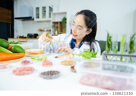 Female food scientist in lab coat and goggles analyzing fresh lettuce roots. Organic farming, hydroponics, nutrition science, and healthy research lab. Female food scientist in lab coat and goggles analyzing fresh lettuce roots. Organic farming, hydroponics, nutrition science, and healthy research lab. 138621330