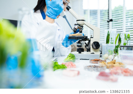 Female scientist testing organic food and plants in biotechnology lab, researching food safety, nutrition, and agricultural innovation. 138621335