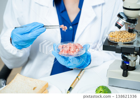 Closeup female scientist testing raw meat in biotechnology lab for food safety, nutrition, and quality research, focusing on food science innovation. Closeup female scientist testing raw meat in biotechnology lab for food safety, nutrition, and quality research, focusing on food science innovation. 138621336