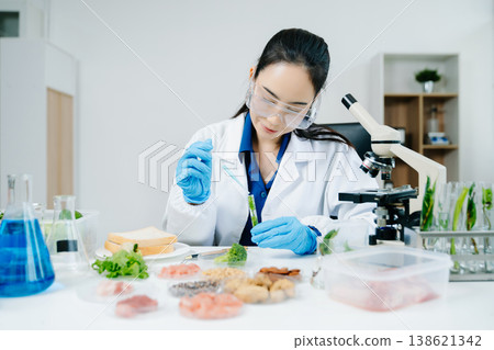 Food scientists woman using microscopes and pipettes in a modern laboratory environment. 138621342