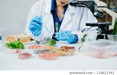 Food scientists woman using microscopes and pipettes in a modern laboratory environment. 138621343