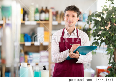 Middle-aged marketer taking record of inventory in household store Middle-aged marketer taking record of inventory in household store 138621351