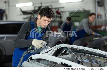 Man auto mechanic polishes body parts by car buffer polisher machine tool Man auto mechanic polishes body parts by car buffer polisher machine tool 138621382