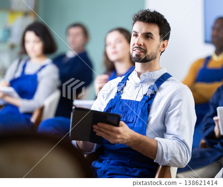 Man in overalls takes notes in an electronic notebook during refresher course Man in overalls takes notes in an electronic notebook during refresher course 138621414