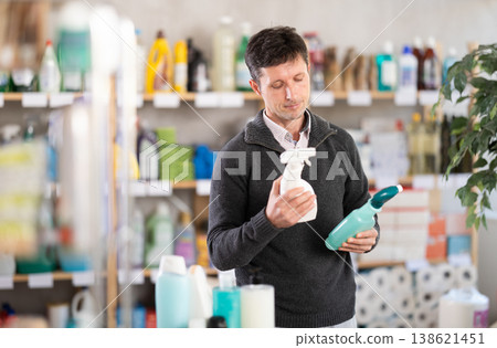 Middle-aged man choosing cleaning spray at department store Middle-aged man choosing cleaning spray at department store 138621451