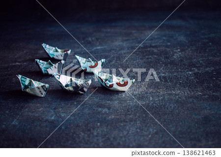 Origami boats folded from dollar bills on dark textured surface. National debt increase, central bank policy, economic instability risks Origami boats folded from dollar bills on dark textured surface. National debt increase, central bank policy, economic instability risks 138621463