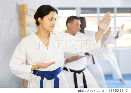 Multinational students repeat position and perform sequence of punches and painful techniques kata 138621542