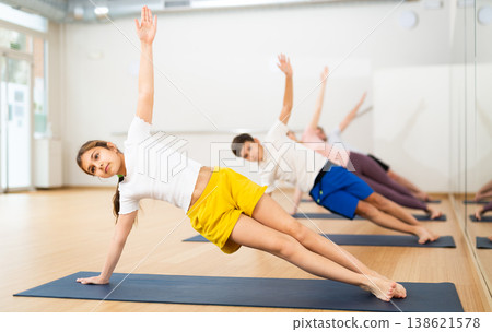Girl practicing side plank with family in gym Girl practicing side plank with family in gym 138621578