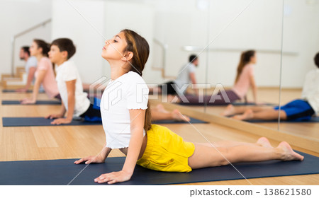 Girl exercising cobra pose during family yoga training Girl exercising cobra pose during family yoga training 138621580