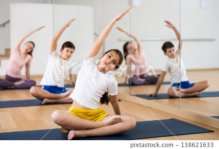 Preteen girl stretching in lotus position during family training Preteen girl stretching in lotus position during family training 138621633