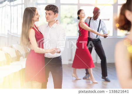 Group of multinational sports people rehearsing social dance in dance hall Group of multinational sports people rehearsing social dance in dance hall 138621641