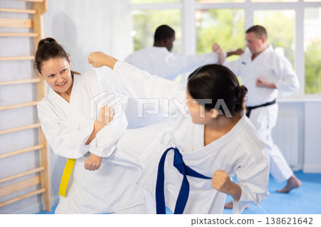 Karate with two female athletes practicing, training and sparring in fight class. Healthy, fit and active women in uniform learning self defense for safety Karate with two female athletes practicing, training and sparring in fight class. Healthy, fit and active women in uniform learning self defense for safety 138621642