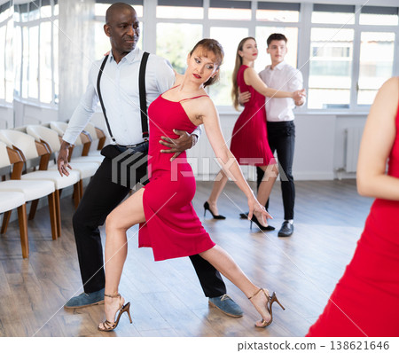 African American and woman in red engrossed in passionate tango during dance class 138621646