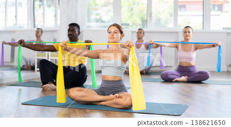 Group of multinational women and men training hands muscles using resistance bands during Pilates studio Group of multinational women and men training hands muscles using resistance bands during Pilates studio 138621650