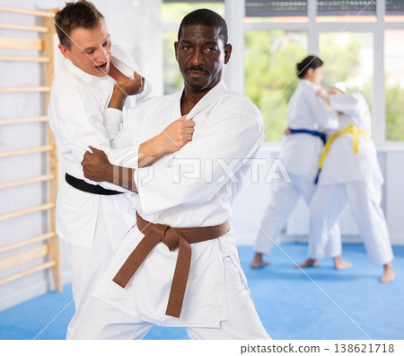 Middle-aged male judo practitioner engaged in wrestling in sports hall Middle-aged male judo practitioner engaged in wrestling in sports hall 138621718