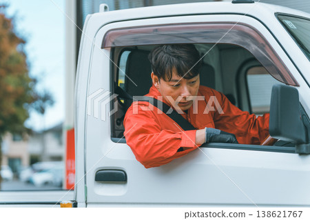 A man in overalls driving a light truck. A man in overalls driving a light truck. 138621767