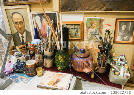 A table with a variety of art supplies, including paintbrushes, cups, and vases 138622738