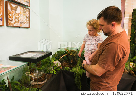 A man and a little girl are looking at a terrarium A man and a little girl are looking at a terrarium 138622771