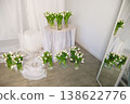 A table with a white cloth and a bunch of white flowers in vases 138622776