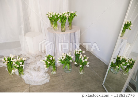 A table with a white cloth and a bunch of white flowers in vases A table with a white cloth and a bunch of white flowers in vases 138622776