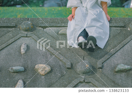 一位女子坐在鵝卵石路上，陷入沉思。 138623133