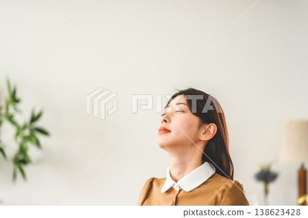 The woman closes her eyes and takes a deep breath. 138623428