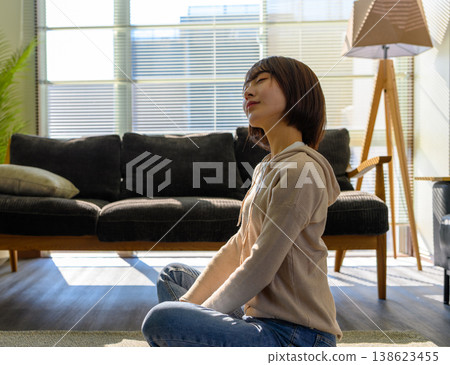 A woman meditates in the living room. A woman meditates in the living room. 138623455