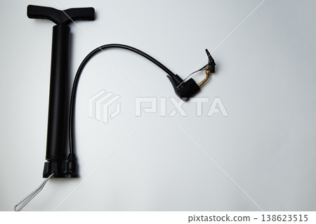 A black pump with several attachments and a leg handle lies on the side on a white background. High quality photo  138623515