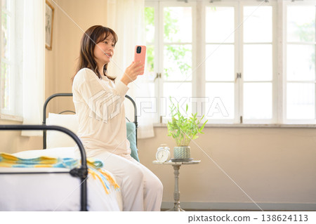 一名婦女在床上的看一個智能手機 138624113