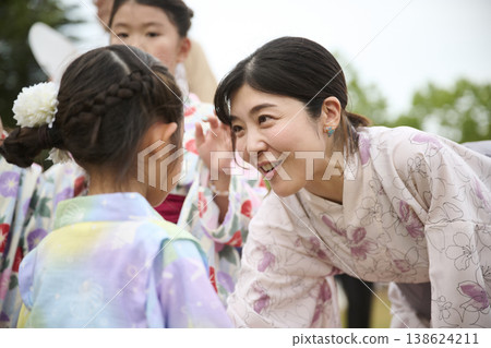 在夏日祭典上,一對身著浴衣的母女面帶微笑地對視著。 在夏日祭典上,一對身著浴衣的母女面帶微笑地對視著。 138624211