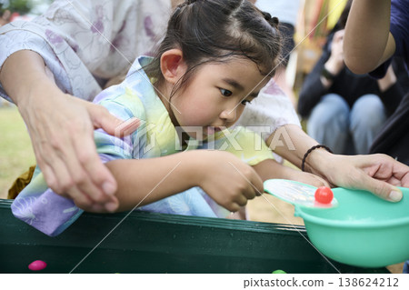 一個穿著浴衣的女孩嘗試抓超級球。 一個穿著浴衣的女孩嘗試抓超級球。 138624212