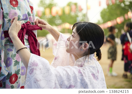 一位母親正在為女兒繫上浴衣的腰帶。 一位母親正在為女兒繫上浴衣的腰帶。 138624215