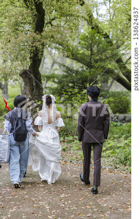 A woman in a wedding dress and a photography crew: A scene from a pre-wedding photoshoot in a park. A woman in a wedding dress and a photography crew: A scene from a pre-wedding photoshoot in a park. 138624837