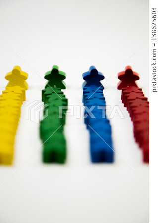 Side view of wooden multi-colored men in focus, who stand at the head of a column of smaller people on a white background. The concept of team competitions, social groups, managers, leaders. High Side view of wooden multi-colored men in focus, who stand at the head of a column of smaller people on a white background. The concept of team competitions, social groups, managers, leaders. High 138625603
