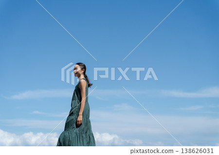 A woman in a dress walking under a blue sky 138626031
