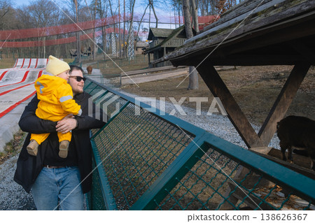 Father holding toddler at petting zoo enclosure 138626367